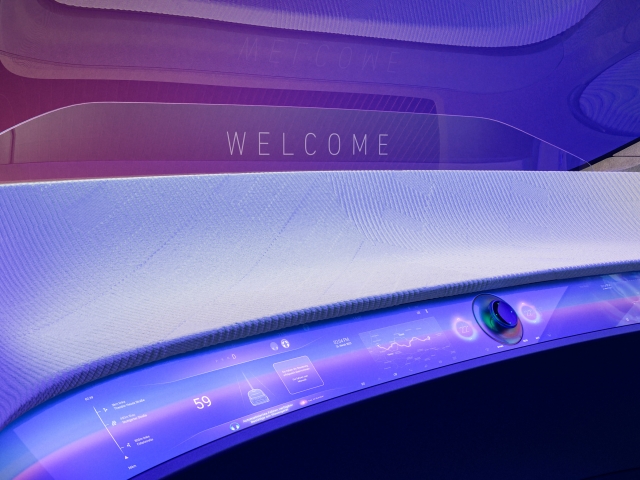 Holistisches-Interieur-in-Lila-mit-durchlaufenden-Screen-worauf-UI-Design-zu-sehen-ist-in-der-mitte-steht-Welcome-auf-Glas-ueber-Mittelkonsole