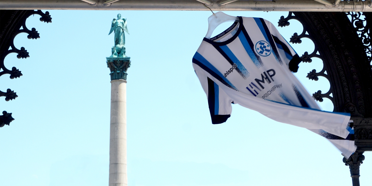 dunkelblau-hallblau-gestreiftes-Trikot-fliegt-mit-dem-Wind-an-einem-weißem-Kleiderbuegel-mit-MHP-Logo-Trikotdesign-von-studiokurbos