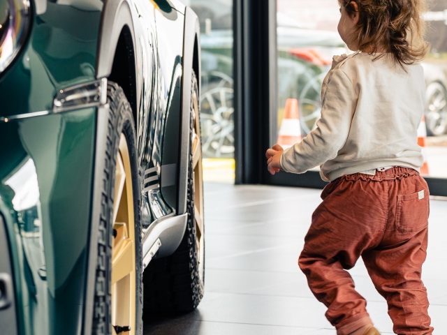 Kind-laeuft-auf-den-gruenen-Porsche-Dakar-zu