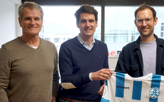 Drei-Maenner-stehen-nebeneinander-und-lachen-in-die-Kamera-waehrend-sie-ein-altest-tirkot-von-dem-Fußballverein-stuttgarter-Kickers-hochhalten