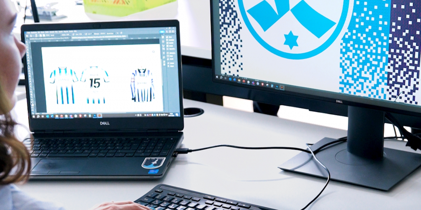 Eine-Junge-Frau-ist-ganz-wenig-links-zu-sehen-sie-schaut-auf-zwei-Bildschirme-mit-Material-und-Logos-der-Stuttgarter-Kickers-darauf